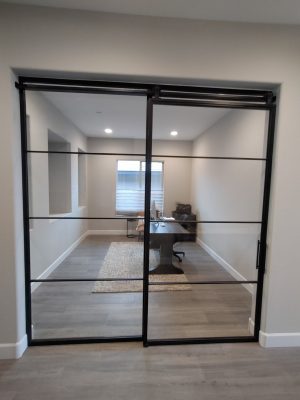 Fixed Metal and Glass Panel and Sliding Barn Door Fixed metal and glass panel beside a sliding black metal and glass barn door to a home office