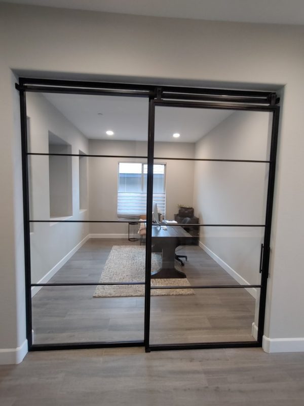 Fixed Metal and Glass Panel and Sliding Barn Door Fixed metal and glass panel beside a sliding black metal and glass barn door to a home office
