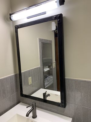 Industrial Mirror with Rivets Industrial framed mirror with rivets above a bathroom sink
