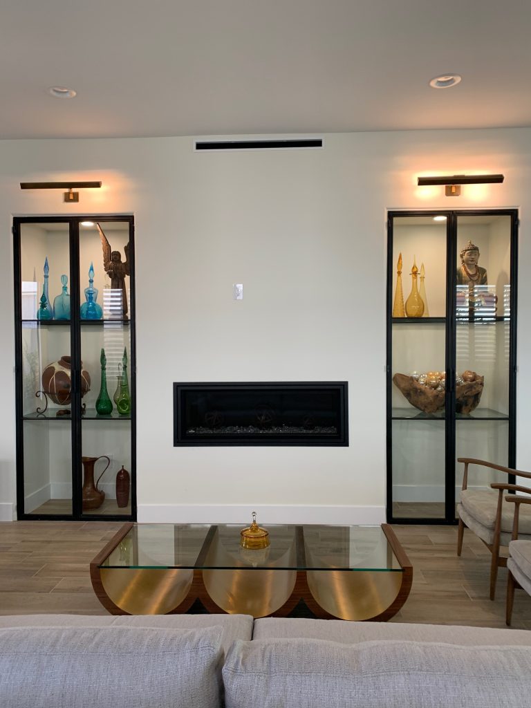 Pair of black metal and glass display cabinets on either side of a fireplace