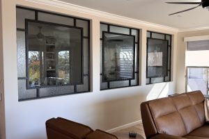 Three black metal interior windows with specialty glass in a living room wall