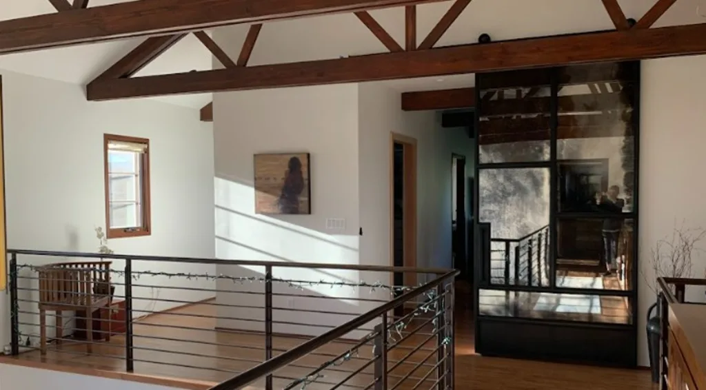 Large random pattern antique mirror and metal barn door in an open loft with a railing