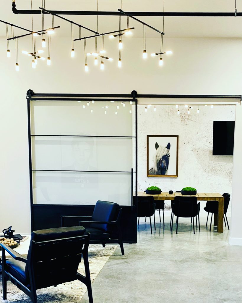 Large single black metal and glass barn door with a solid toe kick in an open office