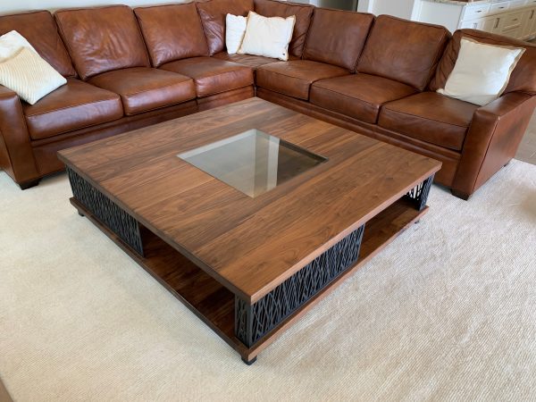 Large square walnut coffee table with a glass centerpiece in front of a leather sectional