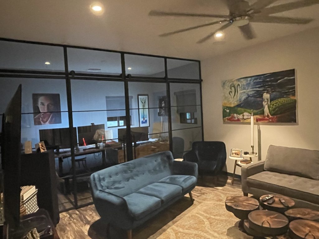 Black metal and glass wall with a sliding barn door, sidelights and transom in a living room