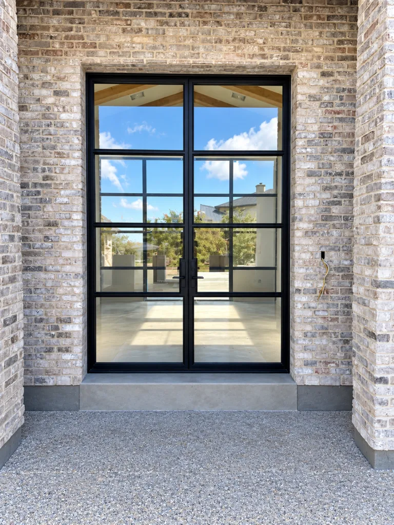 Black metal and glass double front doors set in a brick entry
