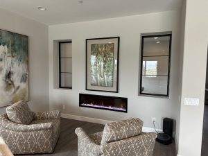 Black metal and glass interior windows on either side of artwork above a fireplace
