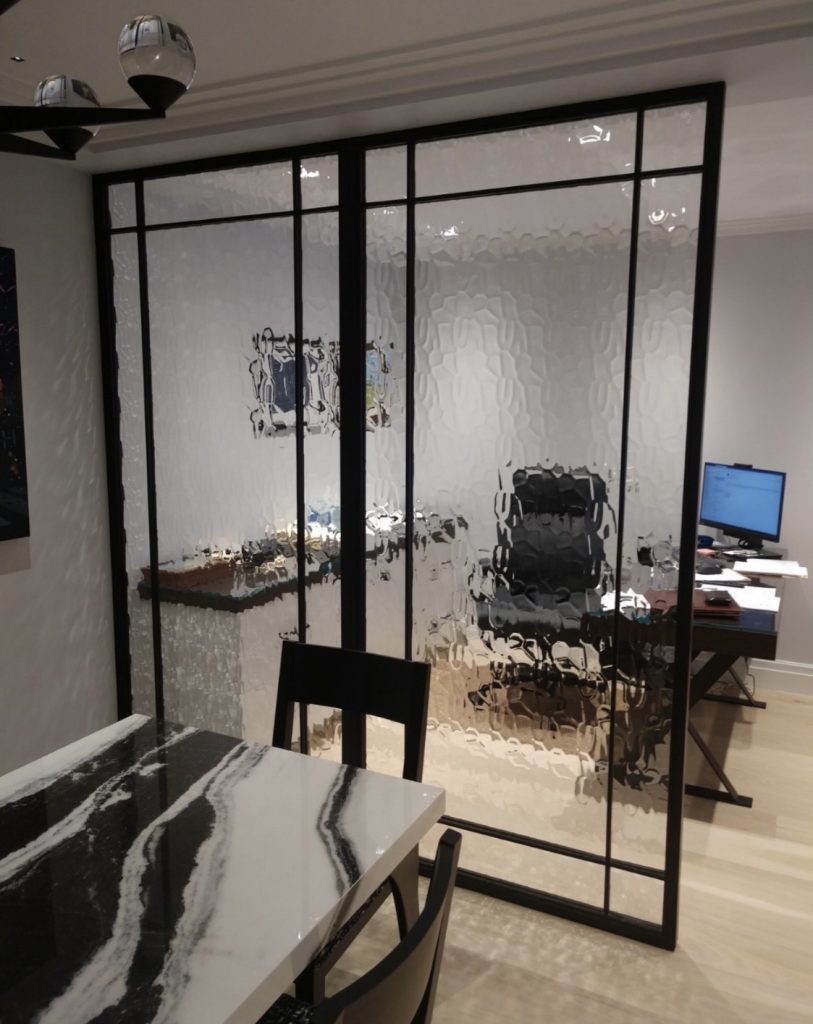 Black metal and clear glass room divider between a dining area and an office