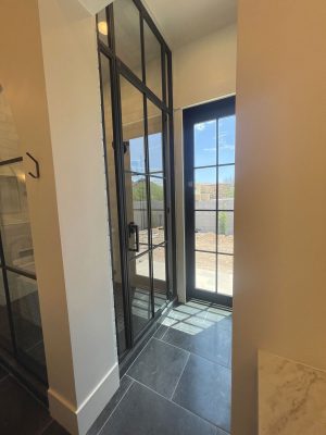 Metal and glass shower door and transom in a tall black frame