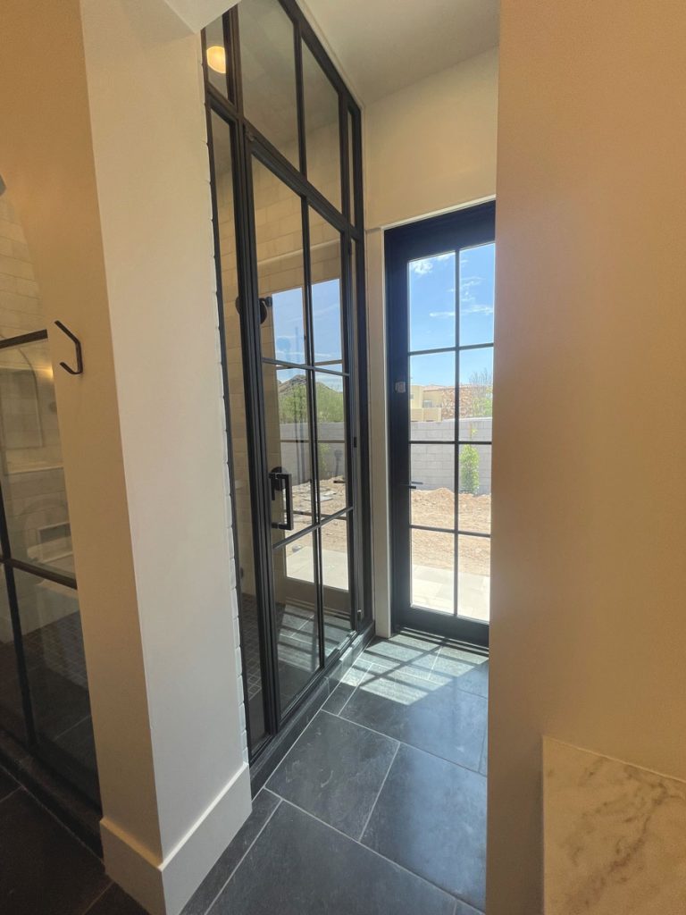 Metal and glass shower door and transom in a tall black frame