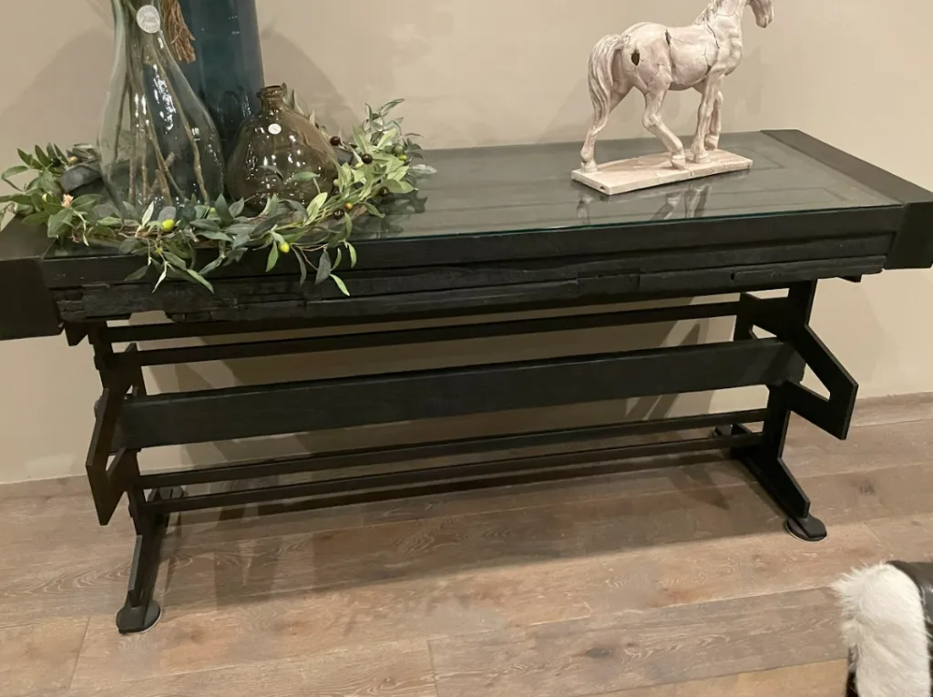 Black metal console table with a glass covered door top and decor