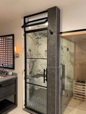 Metal and glass steam shower door with a transom in a black frame