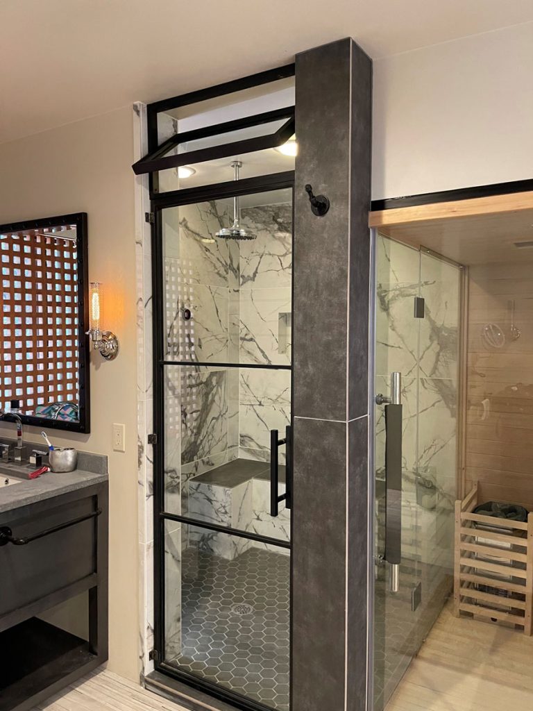 Metal and glass steam shower door with a transom in a black frame
