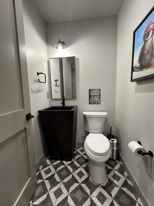 Black metal freestanding sink in a small powder room with patterned tile