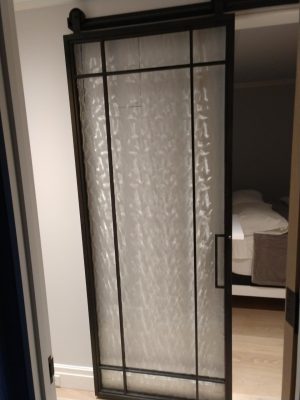 Metal with Specialty Glass Barn Door Black metal barn door with textured specialty glass at a bedroom entry