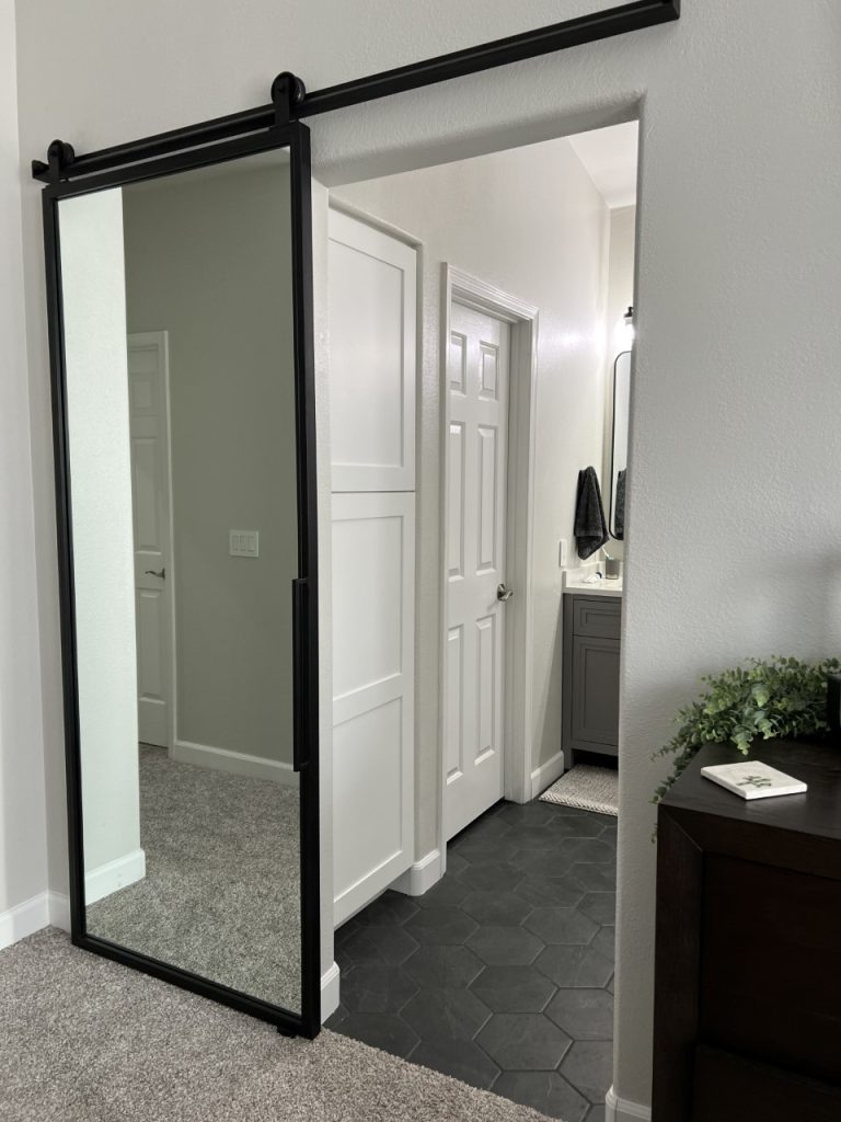 Black metal framed mirror sliding barn door to a bathroom