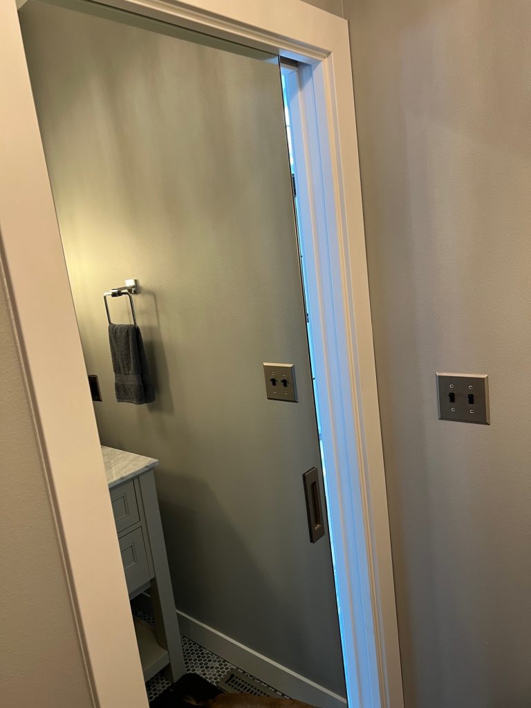 Mirrored pocket door partly open into a bathroom