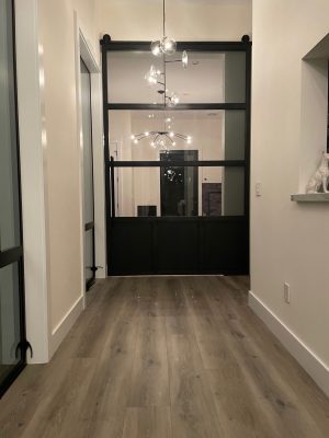 Oversized Steel Metal and Glass Barn Door with Toekick Oversized black steel and glass barn door with a toe kick in a hallway