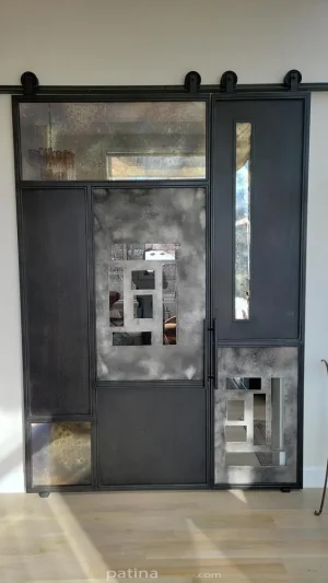 Random pattern steel and aluminum panels with antique mirrors and clear glass barn door