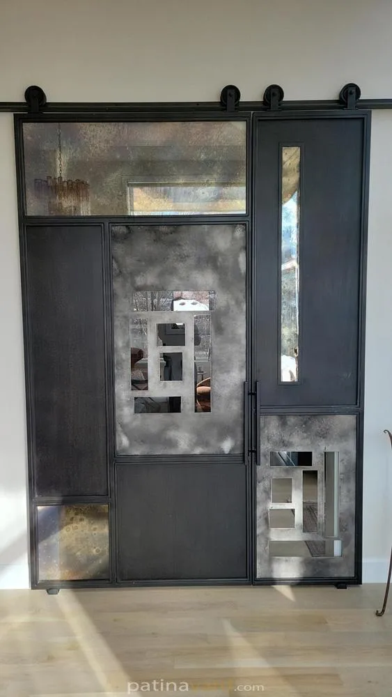 Random pattern steel and aluminum panels with antique mirrors and clear glass barn door