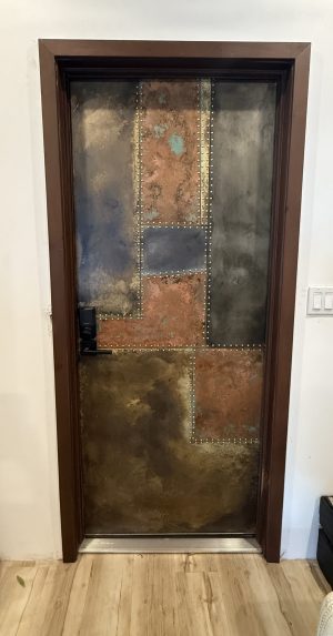 Patinaed copper, brass and zinc riveted patchwork front entry door in Tampa, Florida