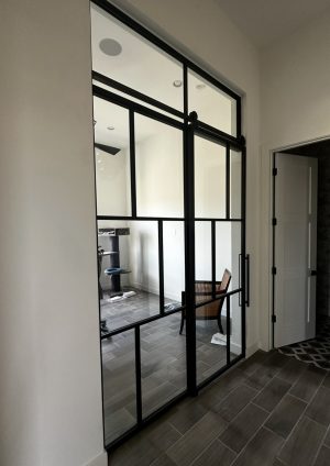 Single Barn Door with Fixed Panel and Transom Single black metal and glass barn door with a fixed panel and transom
