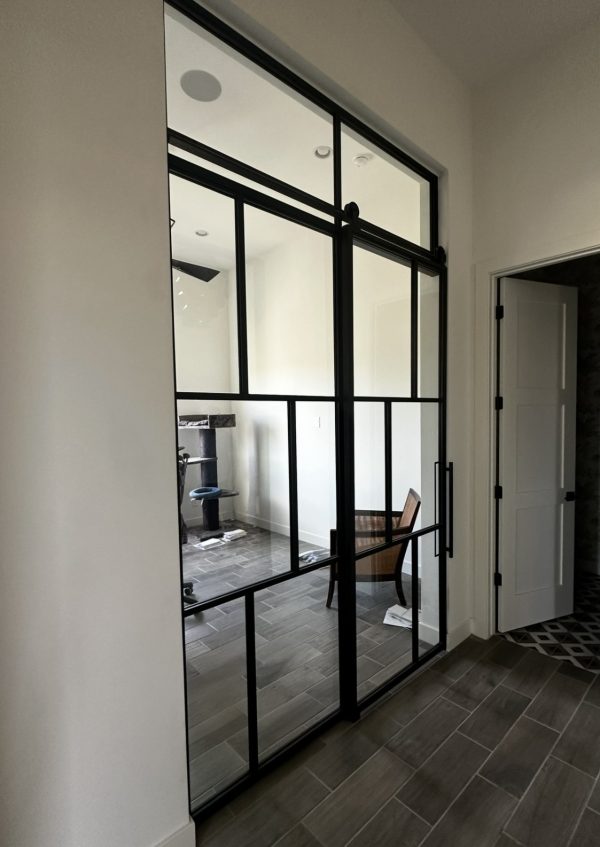 Single black metal and glass barn door with a fixed panel and transom