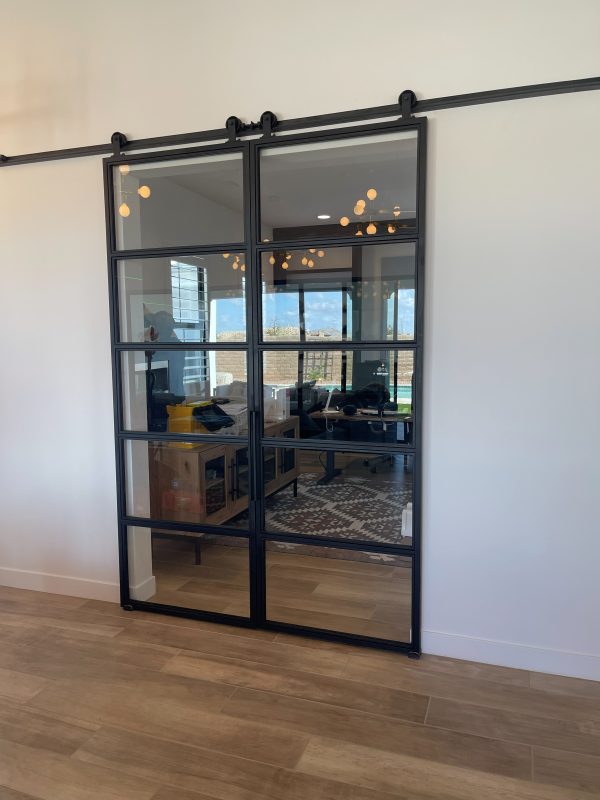 Pair of black metal and clear glass sliding doors on a barn door track