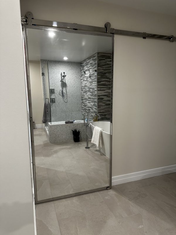 Stainless steel framed mirror barn door to a modern bathroom