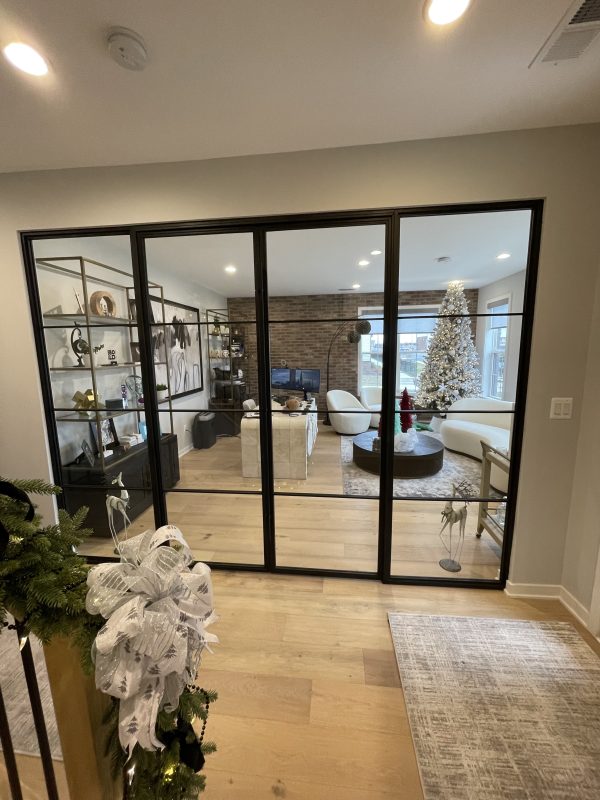 Black steel and glass wall with sidelights and hinged doors into a living room