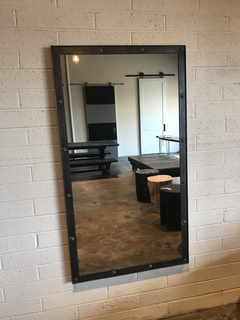 Steel industrial style mirror with rivets in a bedroom