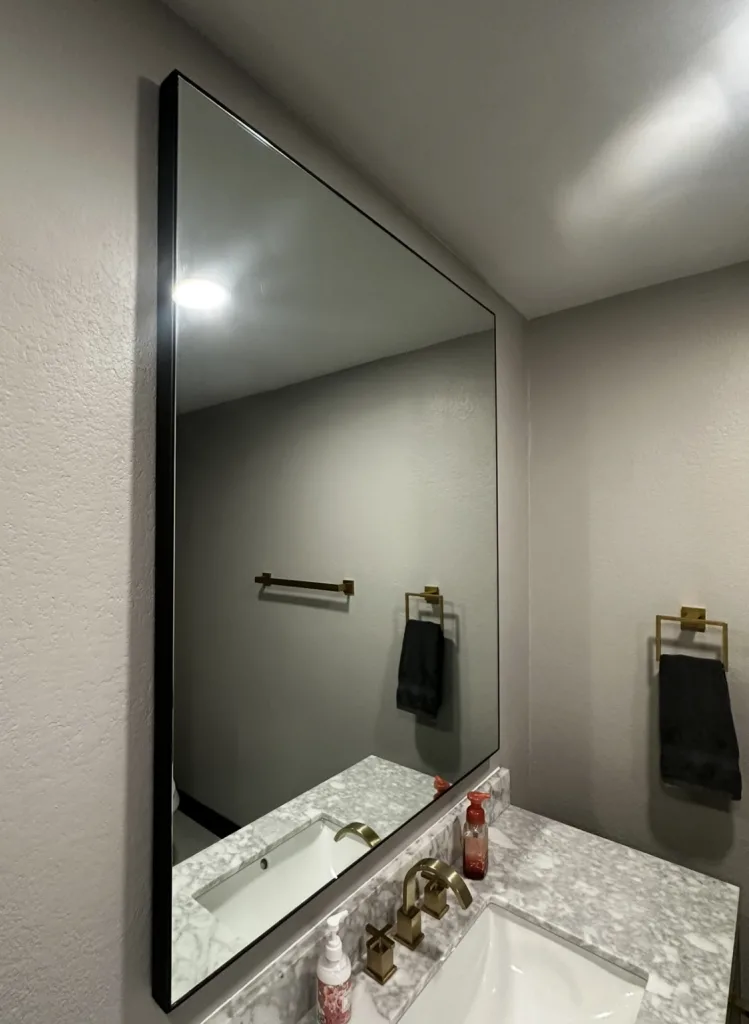 Thin black metal framed mirror above a bathroom vanity