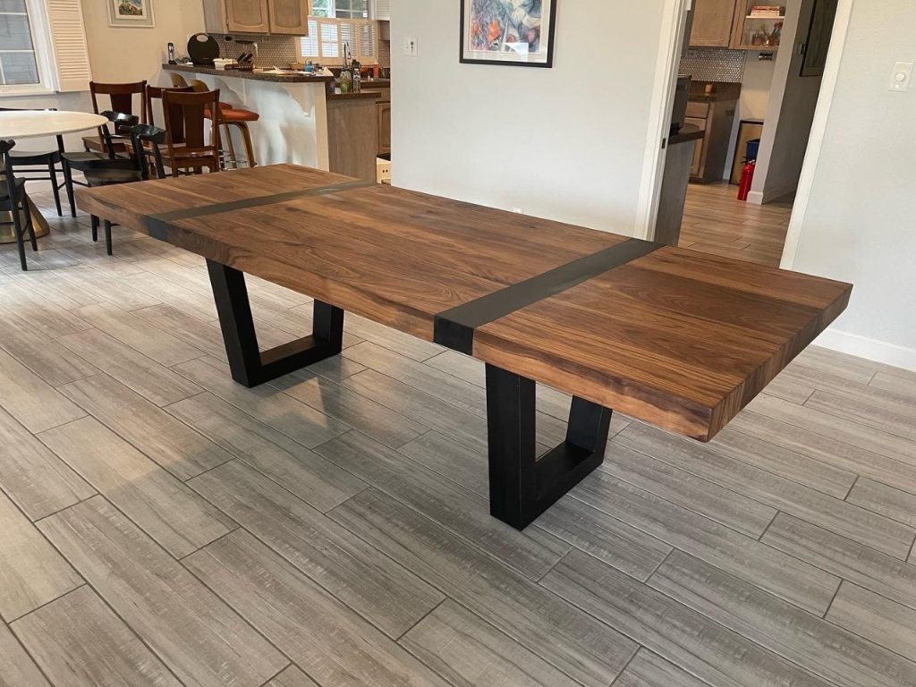 Walnut dining table with a metal band inset and black metal U shaped legs