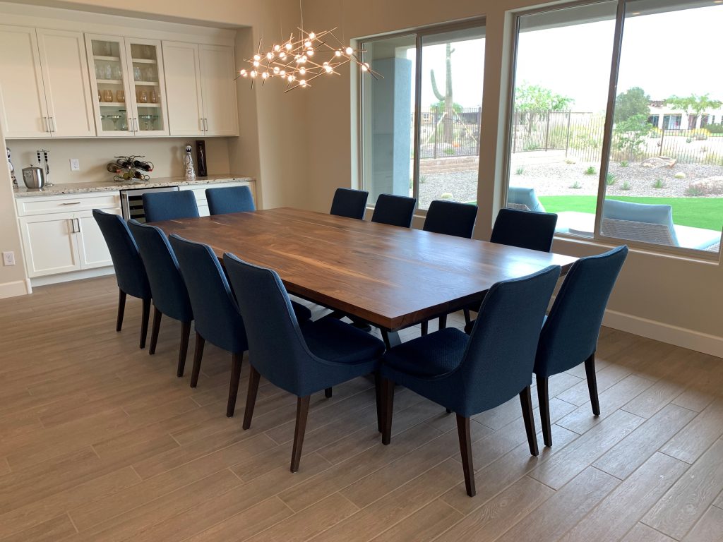 Large walnut dining table with a custom metal base and blue dining chairs