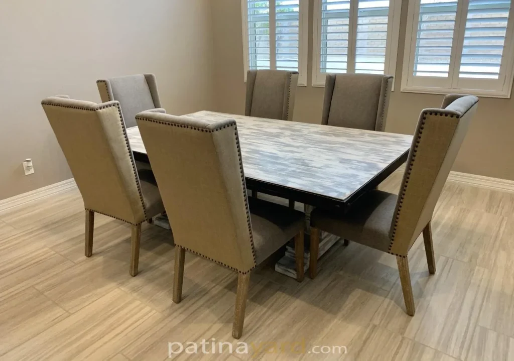 Weathered wood dining table with a chalk paint finish and six upholstered nailhead dining chairs