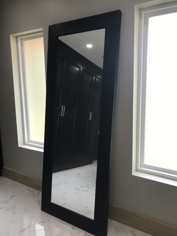 Wood framed full length mirror next to windows